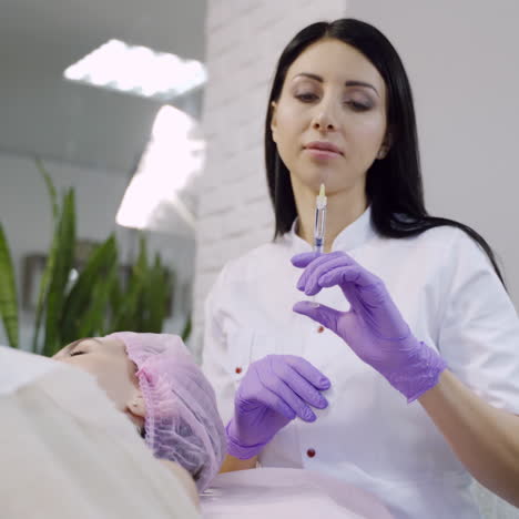 Hands of cosmetologist making injection in face. Rejuvenating facial injections. Aesthetic cosmetology.