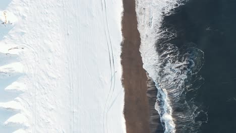 Couple-walking-on-Sandvík-beach-in-Iceland-covered-in-white-snow