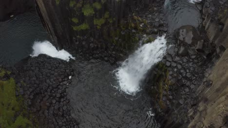 Aerial-top-down-of-splashing-Litlanesfoss-Waterfall-falling-into-icelandic-lake-with-basalt-columns-and-rocks