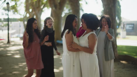 happy brides dancing with guests in summer park after wedding ceremony