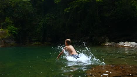 person jumping in a river in the forest