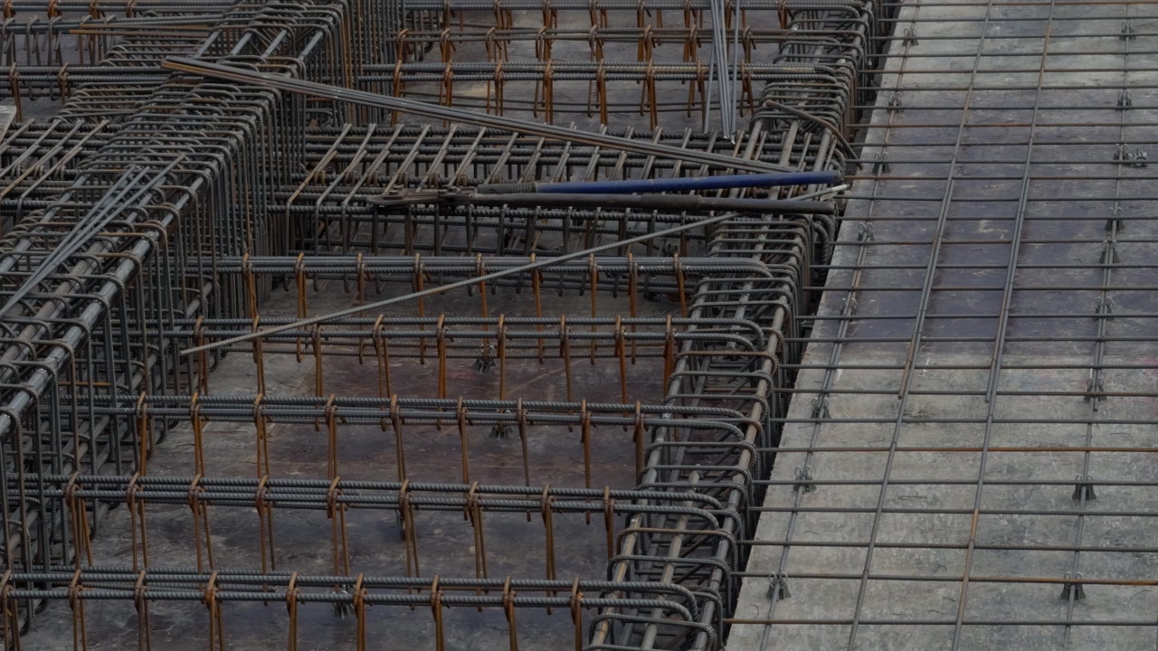 Top view of high-strength steel rebar grids, beam connections, and site details prepared before concrete pouring in an urban redevelopment project. Engineering and infrastructure.