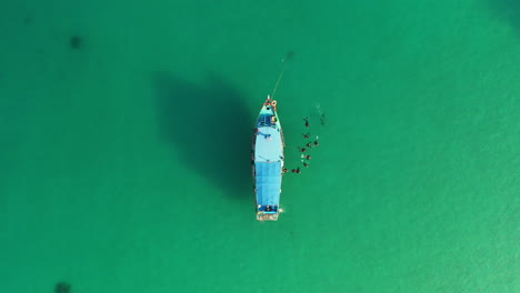 Vista-Aérea-Del-Barco-De-Buceo-Con-Un-Grupo-De-Buzos-Que-Se-Embarcan-En-Aguas-Cristalinas-De-Belleza-Turquesa,-Increíble-Aventura-De-Buceo