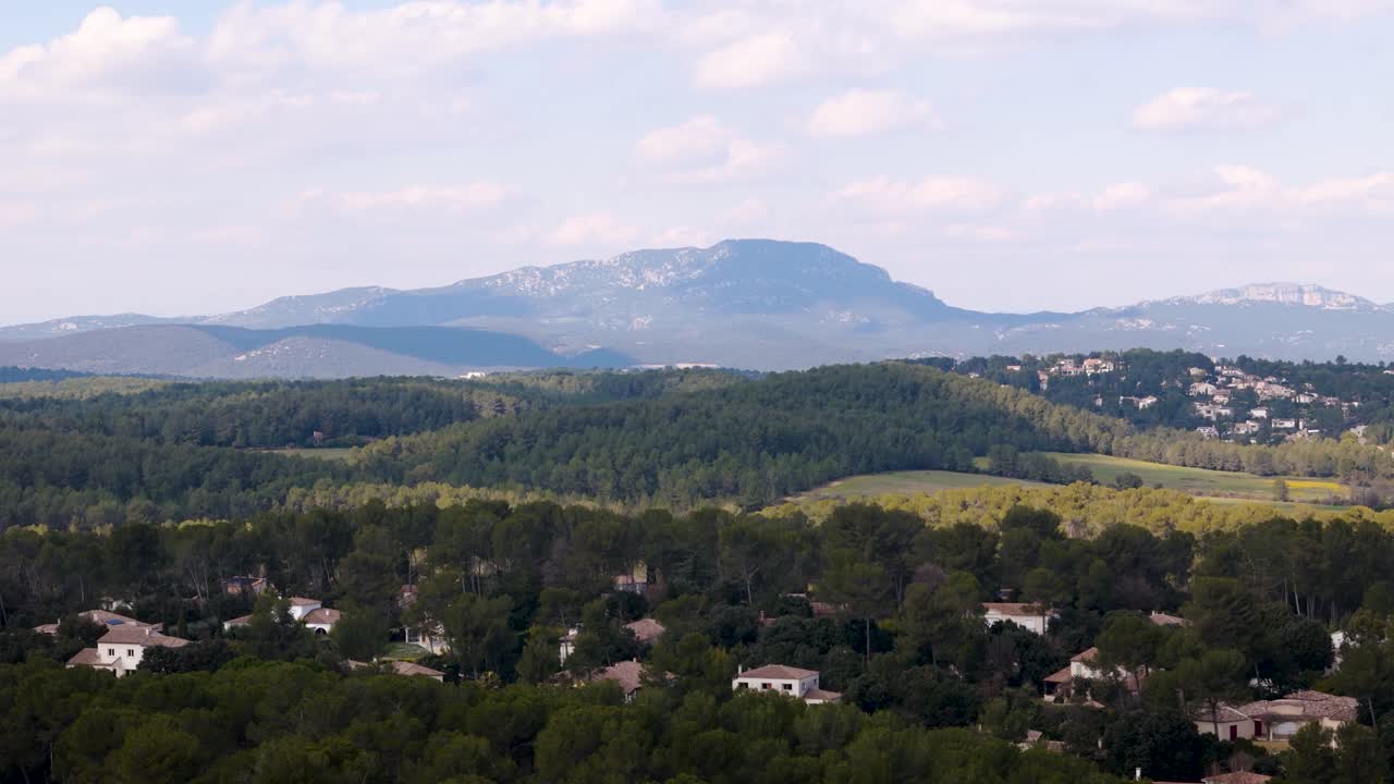 Pic Saint Loup menjulang di balik hutan pinus dan rumah-rumah di lereng bukit di Prancis selatan.