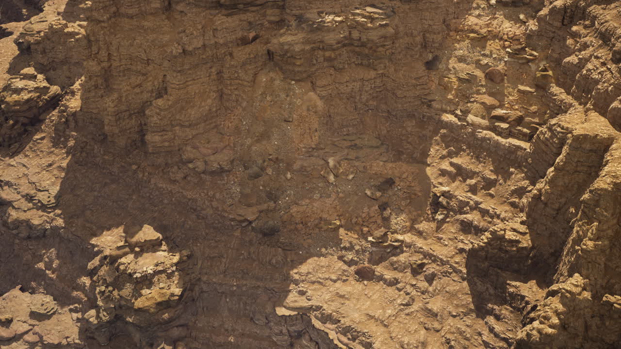 Rocky terrain reveals geological formations at a canyon in midday sun