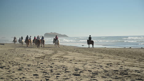 a group of people riding horses at bandon beach, oregon coast