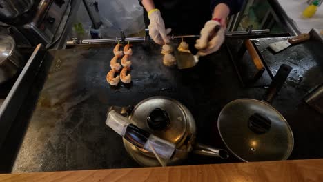 chef prepares shrimp on a hot teppanyaki surface.