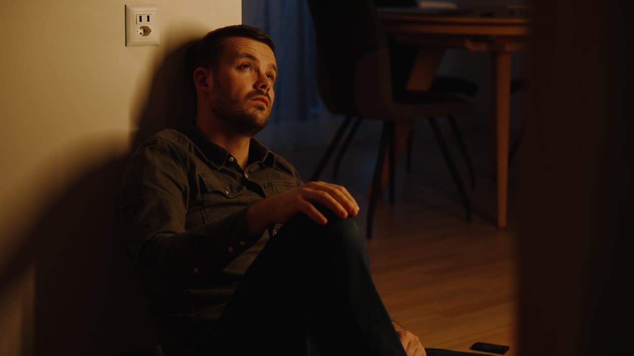 a young man sitting on the kitchen floor and sad, desperate