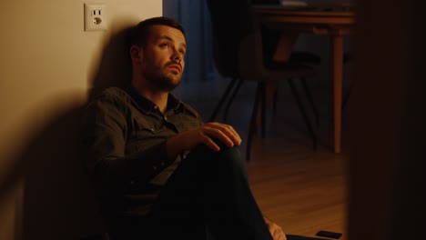 a young man sitting on the kitchen floor and sad, desperate