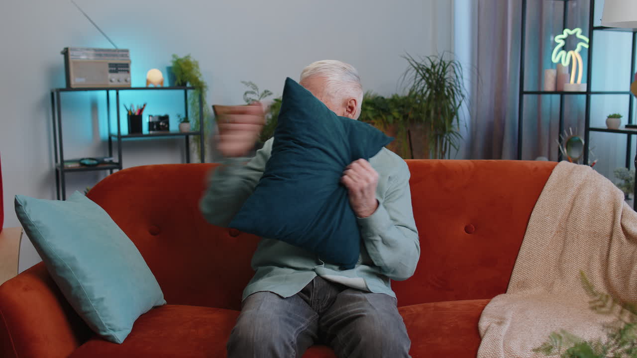 Repair work at neighbours concept irritated man at home cover ears with pillows annoyed by noise