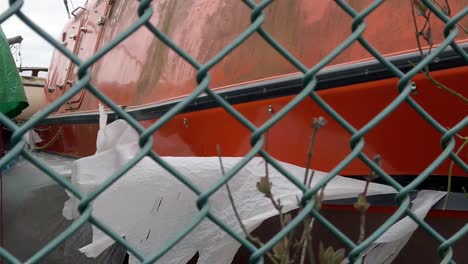 old disused orange rnli lifeboat vessel in secure fenced shipyard pull back