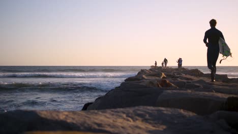 beautiful, calm and peaceful sunset in san diego, shooting down a jetty with people and waves crashing alongside it