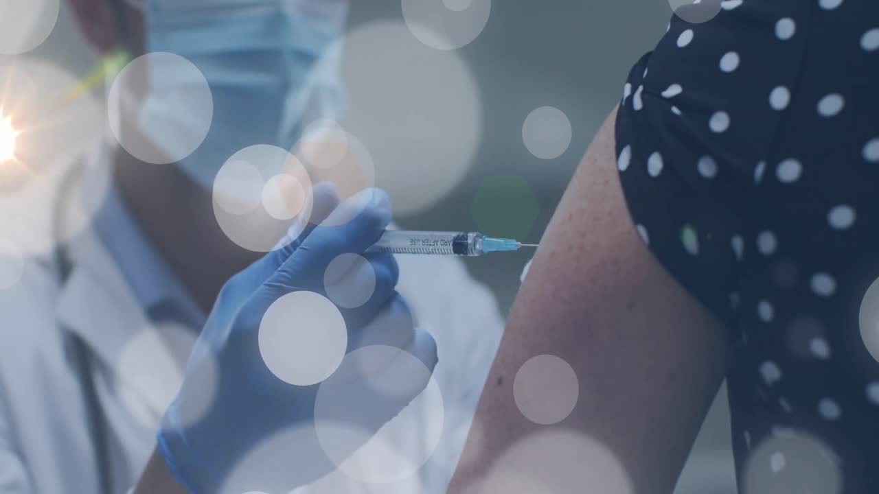 Animation of light spots over diverse doctor and patient vaccinating