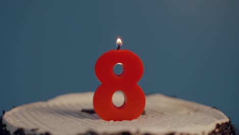 Hand-lights-a-red-8-year-old-birthday-candle-with-lighter-on-white-cake-with-chocolate