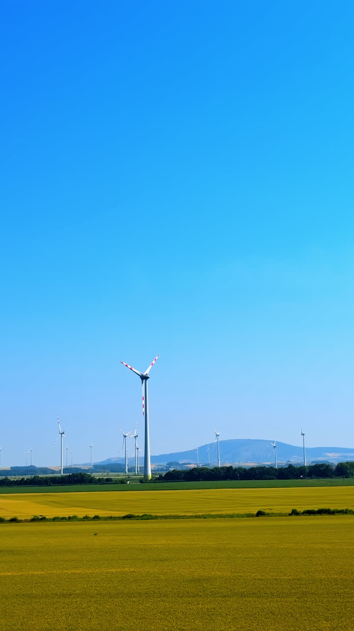 Wind turbines against a clear blue sky. Wind turbines stand tall in a flat landscape under a vibrant blue sky, showcasing renewable energy in action