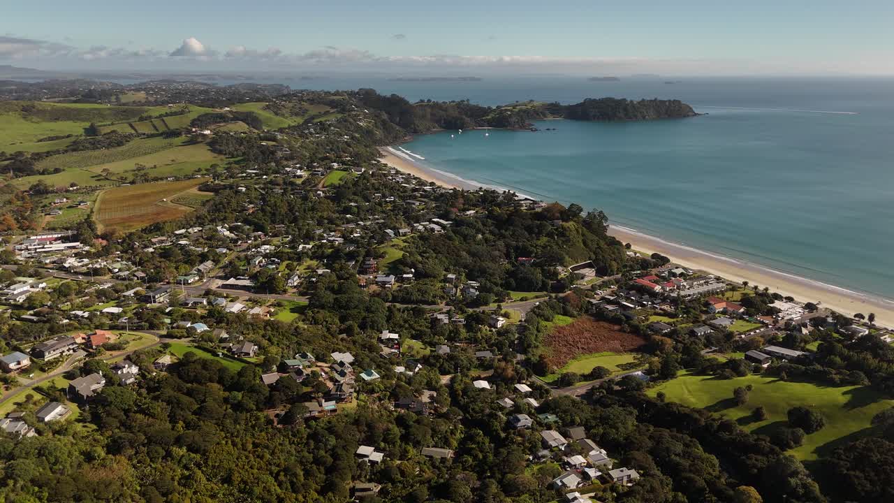 Onetangi Beach, Waiheke Island, white sand beach, and turquoise ocean with lush green hills and vineyards in background. New Zealand. Aerial drone panoramic view