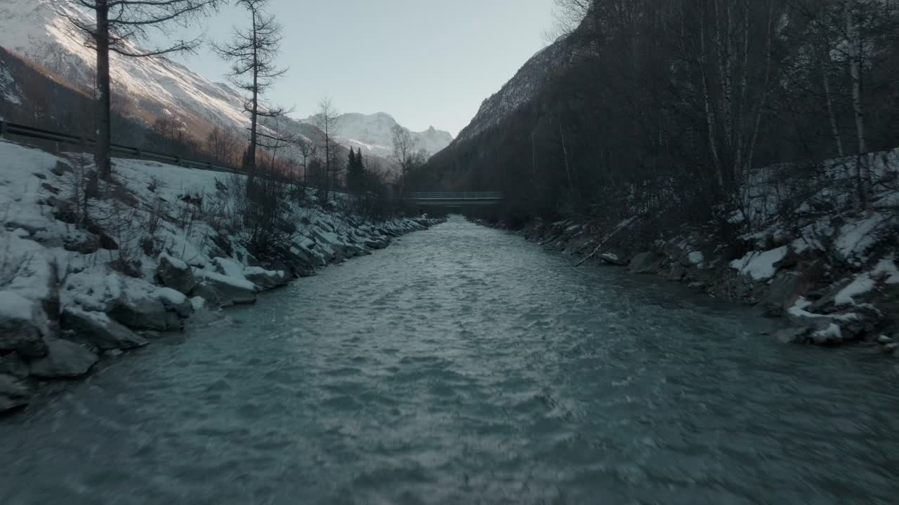 carro sobre el agua fría del río suizo con nieve en las orillas del río en los alpes suizos con un panorama épico de montaña