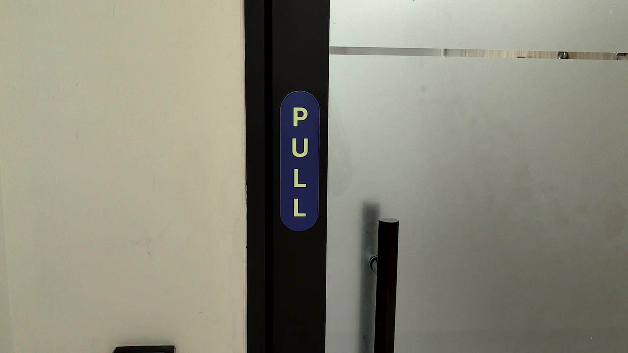 Nærbillede af et 'træk'-skilt på en glasdør i en kontor-, hospitals-, detail- eller erhvervsbygning. Nyttigt for tilgængelighed, navigation, facility management og arbejdspladskoncepter