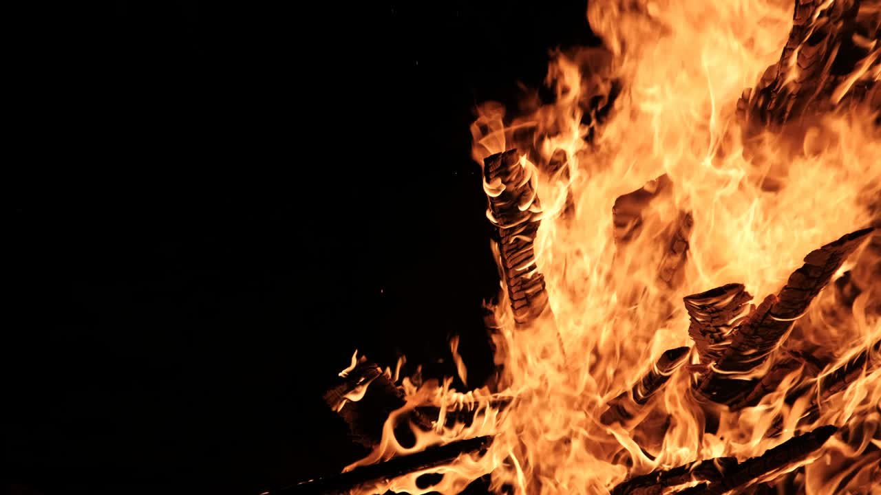 una gran hoguera arde por la noche en cámara lenta sobre un fondo negro en la naturaleza