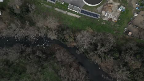 aerial view capturing sustainable wastewater treatment facility with solar panels generating renewable energy alongside river in rural french landscape