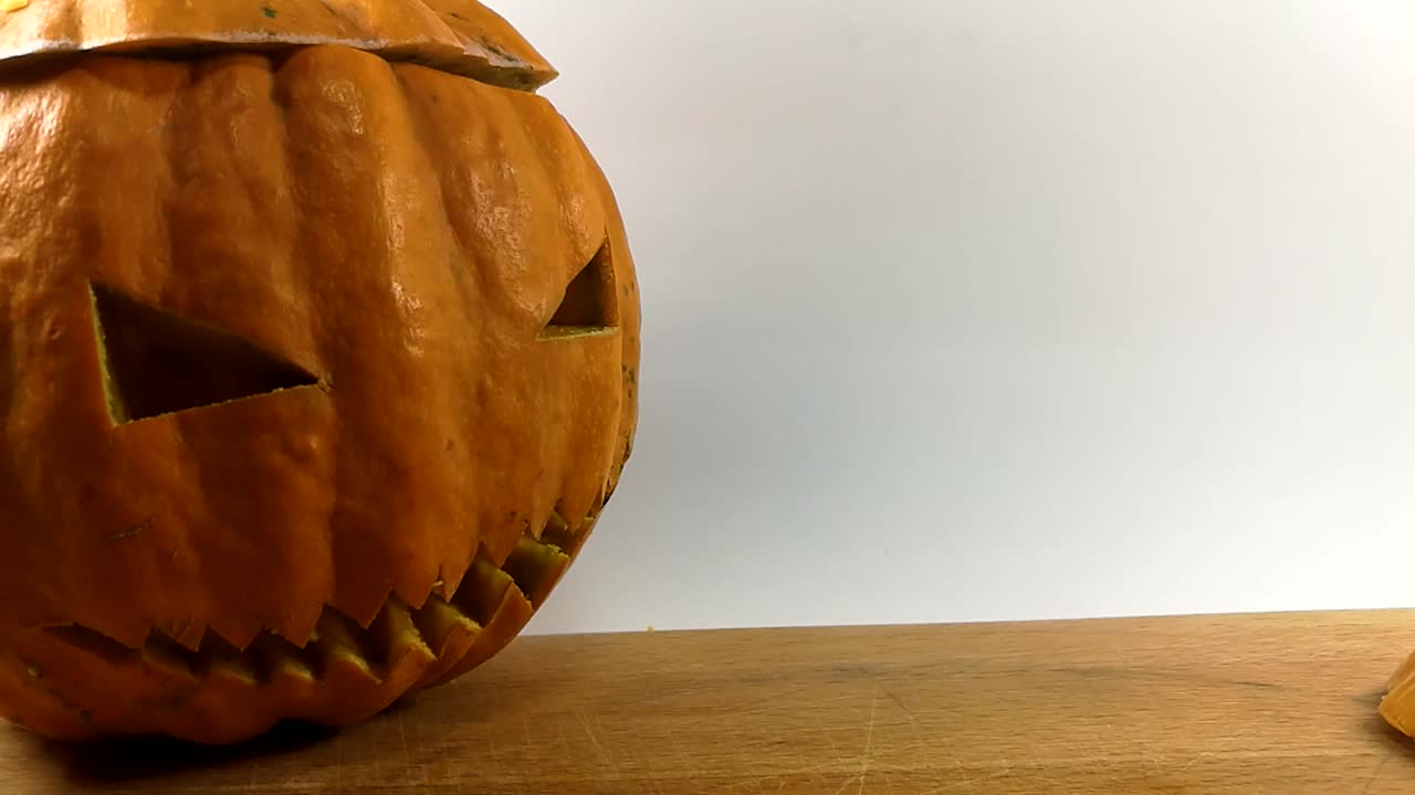 carpintería de calabaza parte 13, persona colocando una pequeña calabaza de halloween tallada al lado de una más grande sentada en una tabla de cortar de madera, quieto, aislado