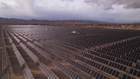 Imágenes-Aéreas-De-Drones-Del-Campo-De-Paneles-Solares-En-El-Parque-Nacional-Del-árbol-De-Joshua-En-Un-Día-Soleado-Con-Arco-Iris-En-El-Fondo,-Inclinación-Vertical-Lenta