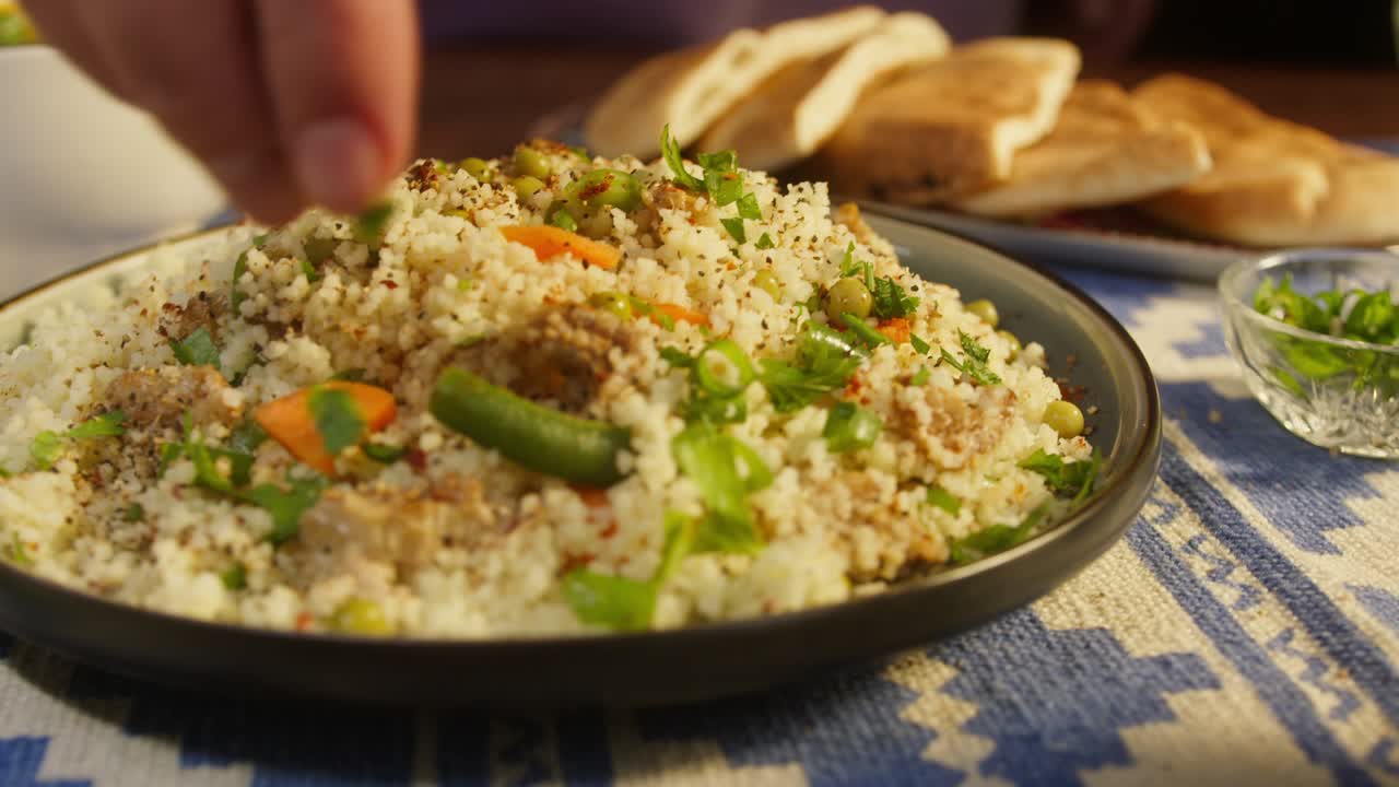 salpicando la vegetación en el cuscús con pollo en la mesa de primer plano. cocina árabe. pita y bulgur en el fondo. cultura tradicional de oriente medio. delicioso arroz con carne. concepto de comida casera