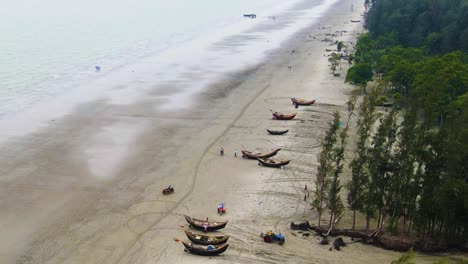 una fotografía aérea de una costa en bangladesh con barcos tradicionales y una línea de árboles