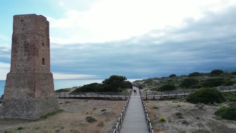 drone video of a beach in southern spain, where people enjoy taking a walk along a wooden path along the beach.