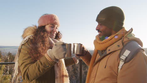 couple enjoying hot drink on a snowy mountaintop