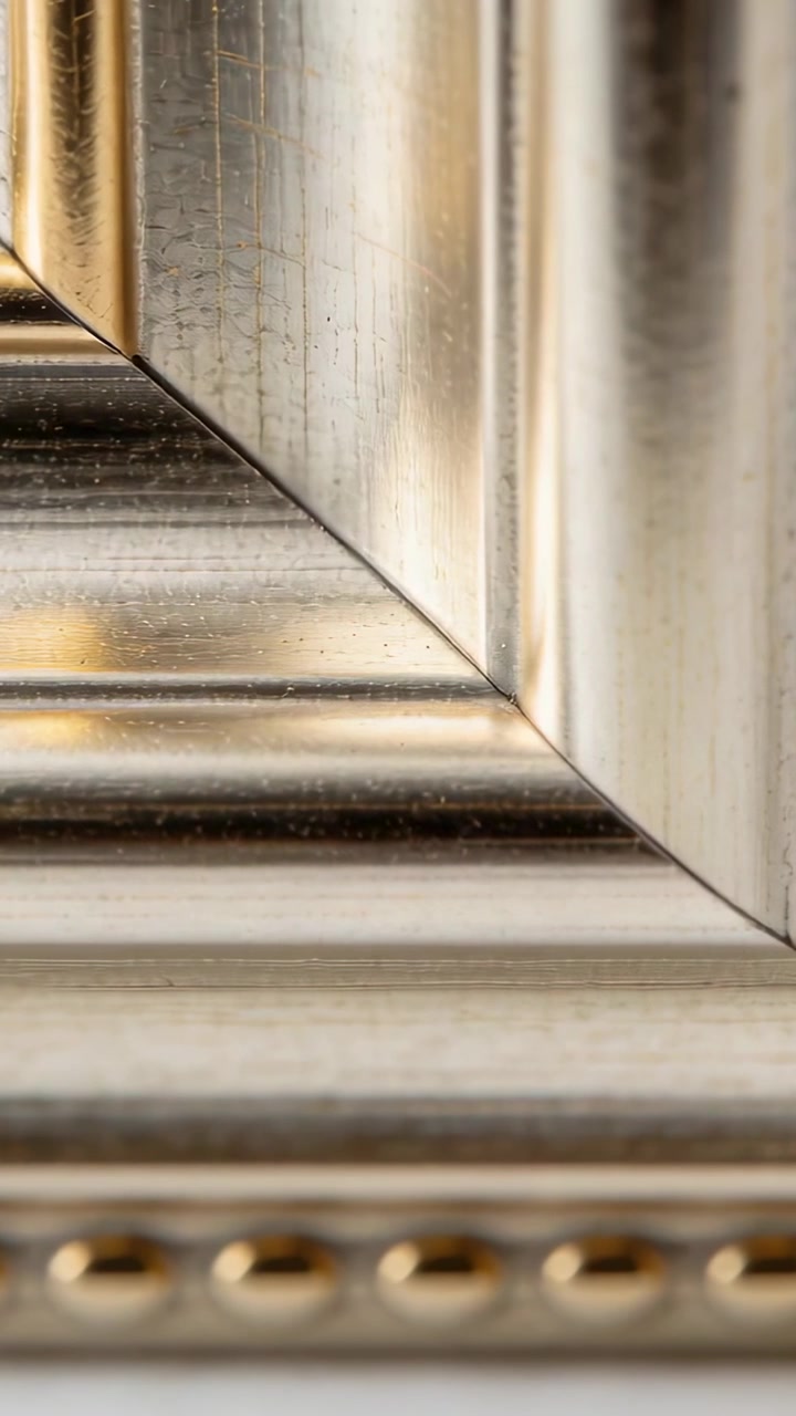 Vertical video: Showing mitered metal frame corner on wall catching shifting light, revealing beads