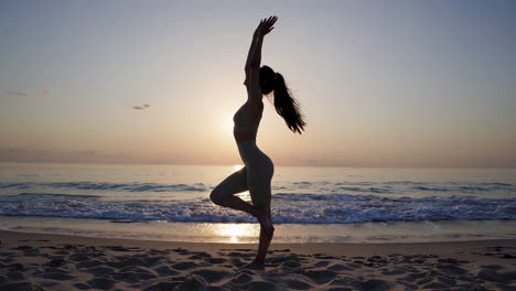 mujer practicando yoga en una playa al amanecer