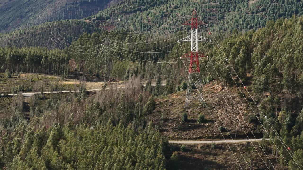 Electric power lines and towers over mountains and forests zoom lens shot