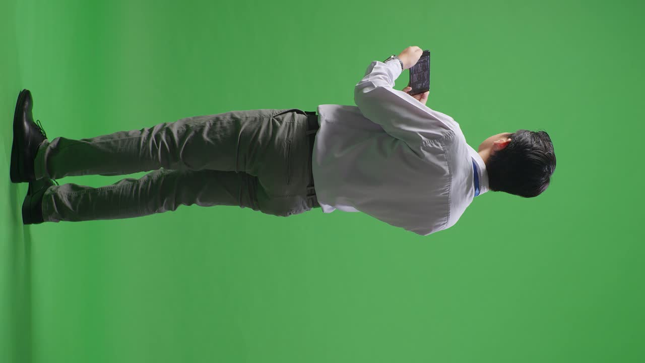 초록색 화면에 있는 태블릿을 보는 남자