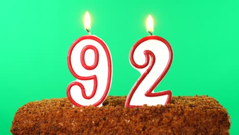 cake with the number 92 lighted candle. chroma key. green screen. isolated