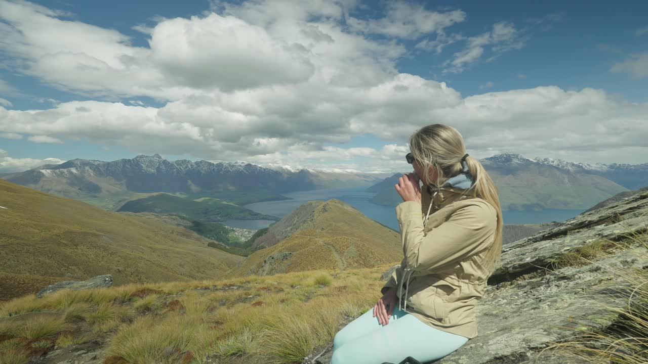 벤 로몬드 트레일에서 멋진 전망을 즐기면서 샌드위치를 먹는 금발 여성 관광객