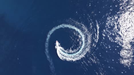 motor boat spinning in circle, top down drone shot of vessel and wake