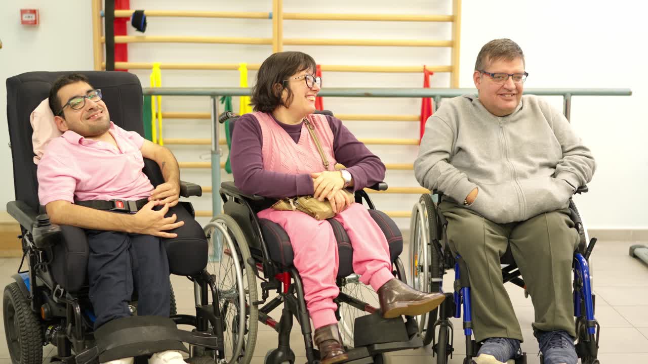 Persone disabili felici in sedia a rotelle che parlano e ridono in un centro di riabilitazione