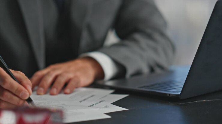 mani del manager che scrivono il rapporto con la penna da vicino. lavoratore occupato che consulta il computer