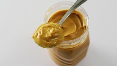 Video-of-close-up-of-jar-of-peanut-butter-on-white-background