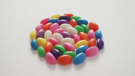 video of close up of multi coloured sweets forming circle over white background