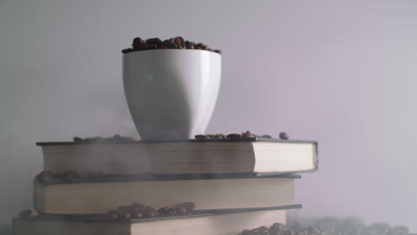 white coffee mug, surrounded by roasted coffee beans on a stack of books, rotating on a display turntable