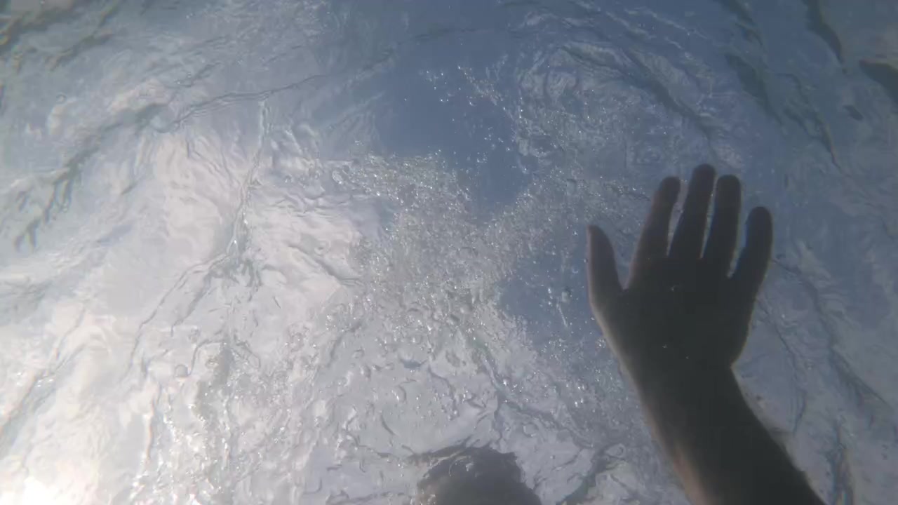 Slow motion underwater view of a swimmer's head breaking the surface with bubbles and a splash, Cote d'Azur, France