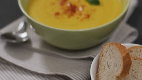 video of cream vegetable soup in bowl on grey table with bread