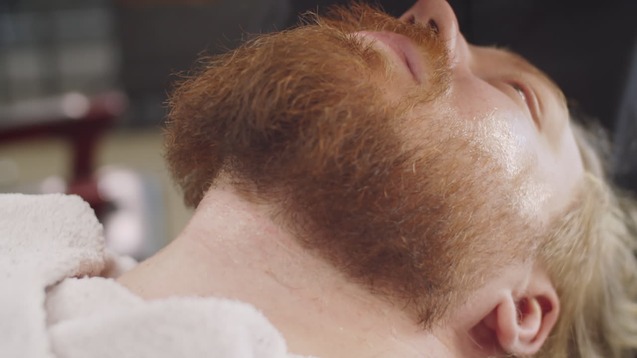 las manos del barbero aplicando loción a la piel del hombre