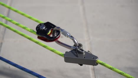 Rope-being-pulled-through-a-safetey-pulley-attached-to-carabiner,-climbing-equipement-inspection