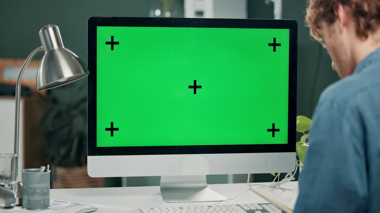 Man working at a computer with a green screen
