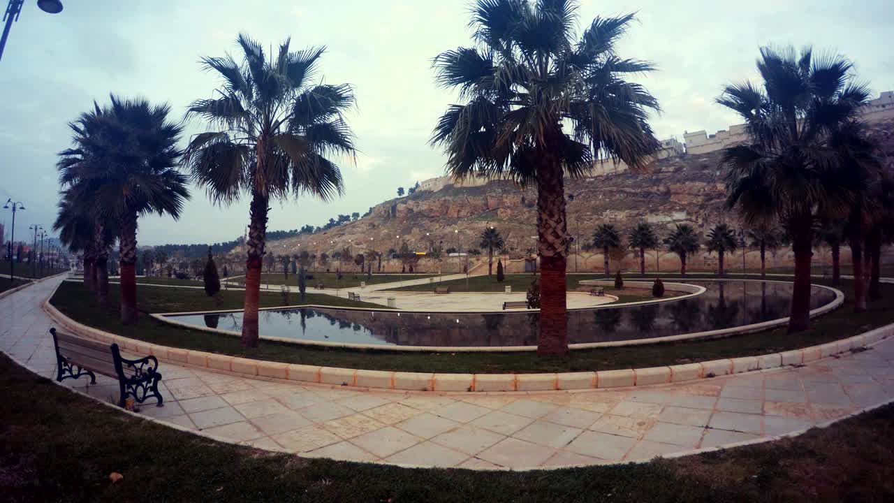 Semicircular Pool with Palms around on Background Ancient Urfa Cavern Houses Wintry Evening