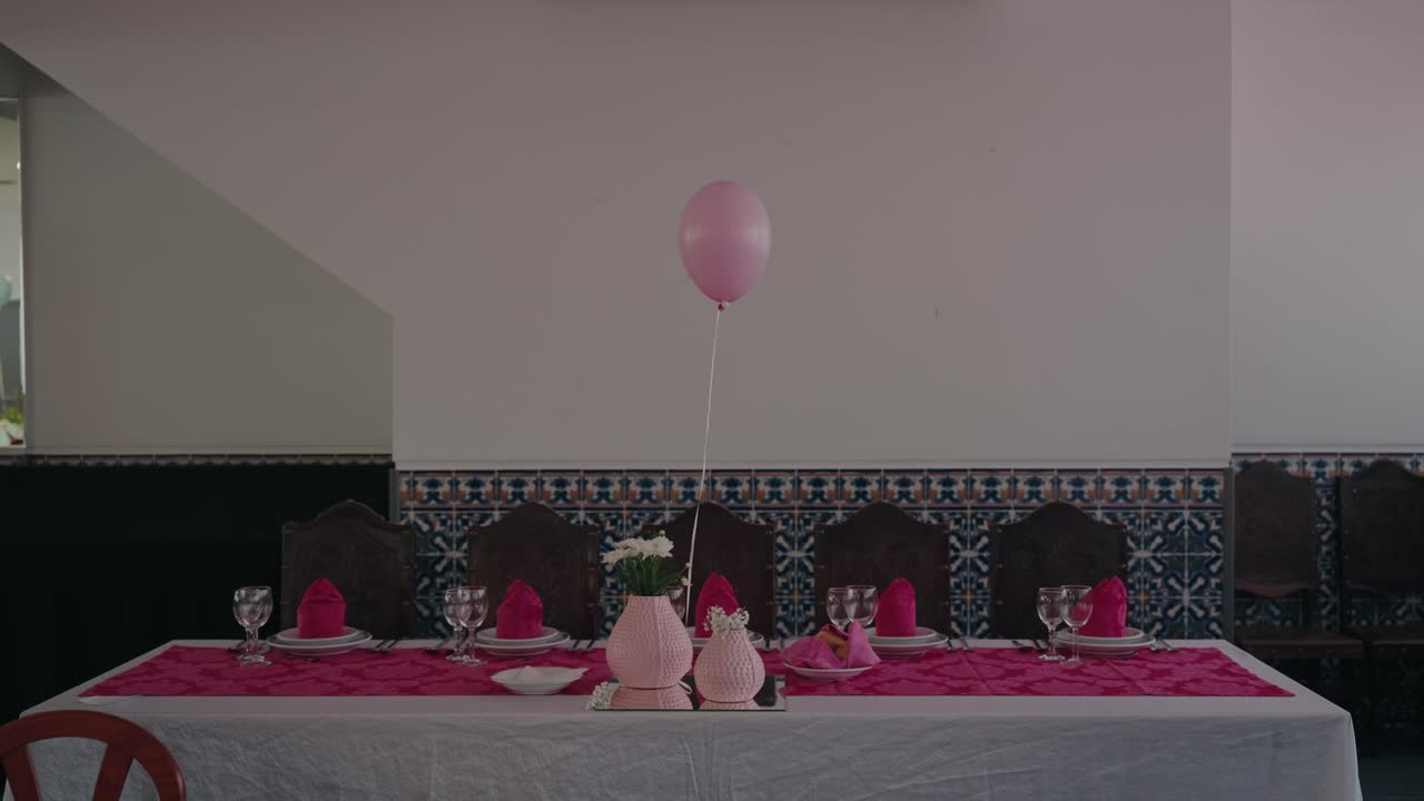 Decorated table with pink accents and balloon centerpiece prepared for celebration