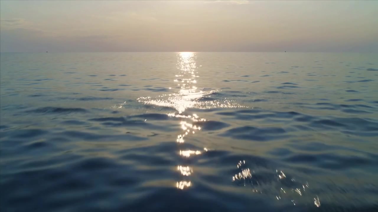 Il sole che si avvicina all'orizzonte proietta un percorso verticale sul mare all'ora d'oro, con le increspature che disperdono il riflesso.